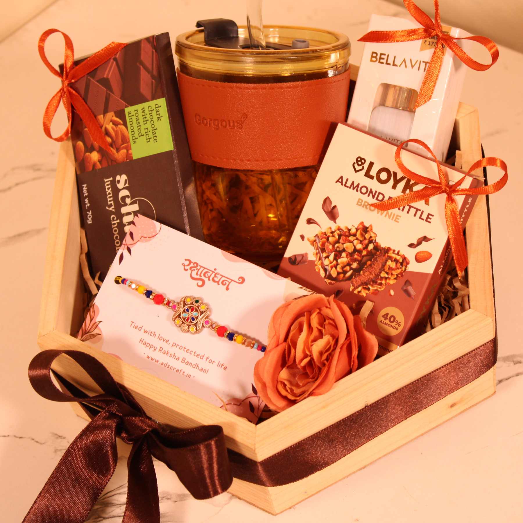 Exclusive Rakhi gift basket for him with sipper, chocolates, perfume, and festive ribbon decoration.