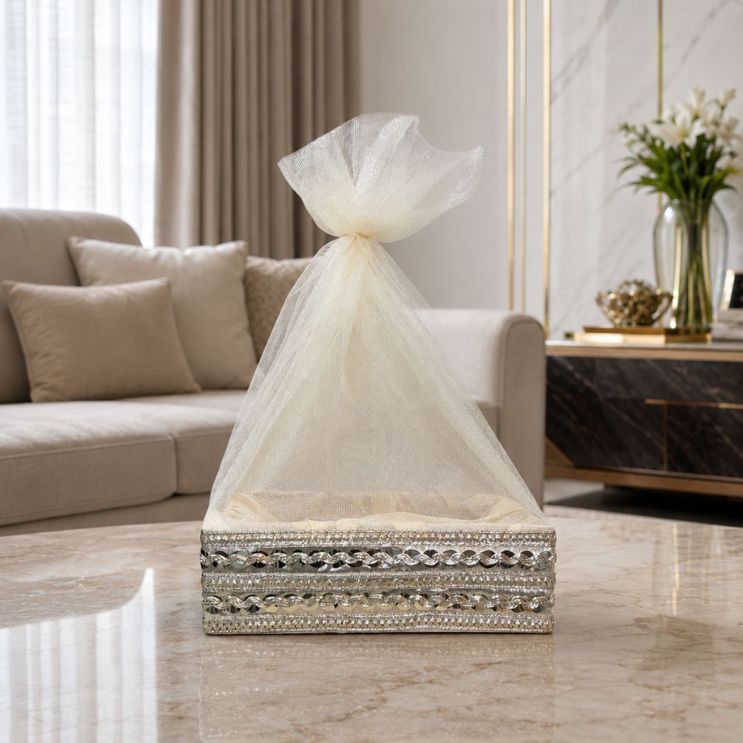 Close-up of cream organza net potli cover with silver decorative lace and mirror-style border work