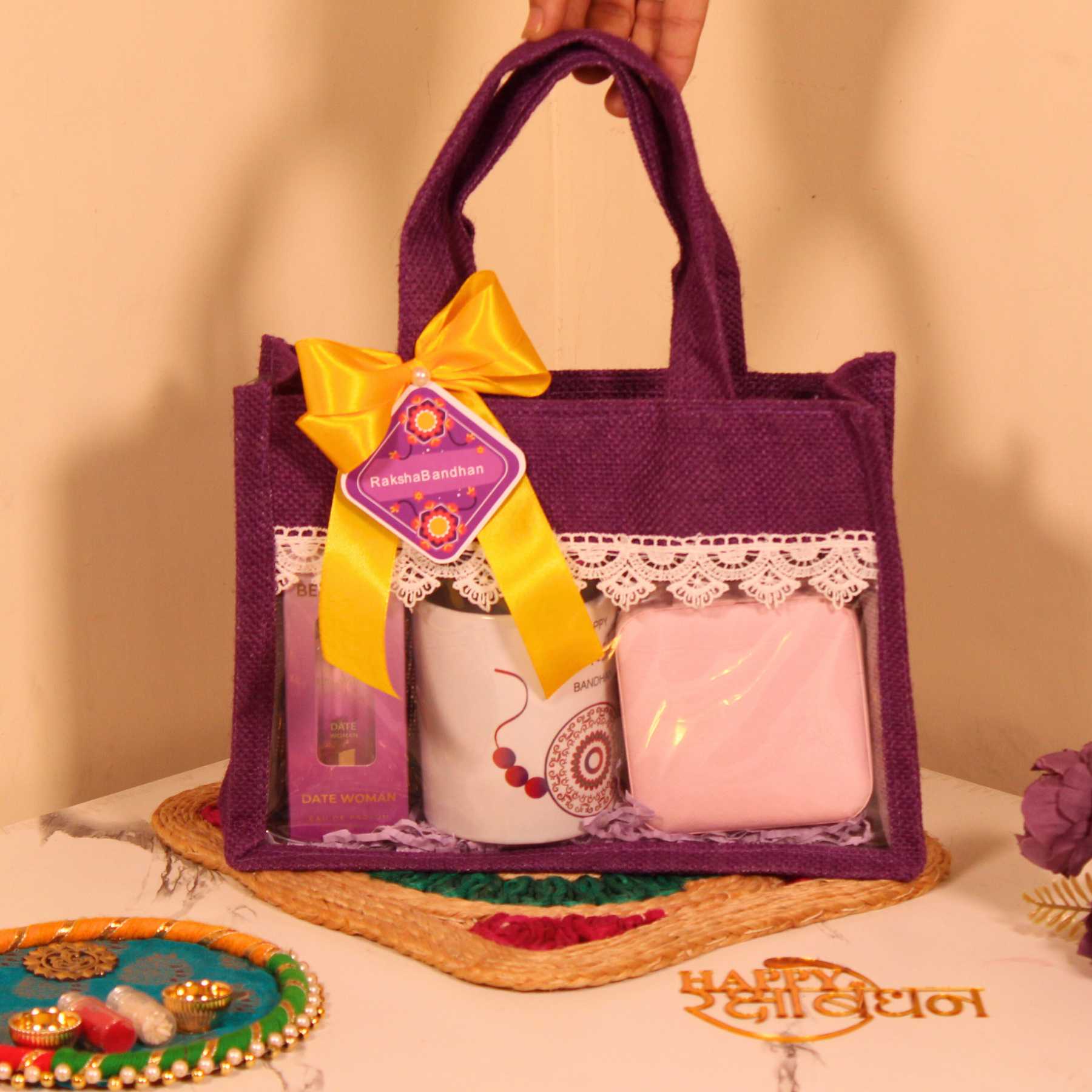 Rakhi Gift Hamper for Her – Purple Jute Bag with Perfume, Mug, Jewellery Organizer & Party Mix