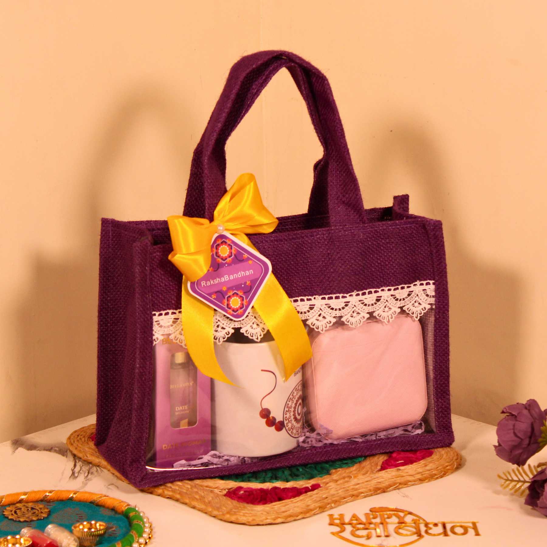 Rakhi Gift Hamper for Her – Purple Jute Bag with Perfume, Mug, Jewellery Organizer & Party Mix