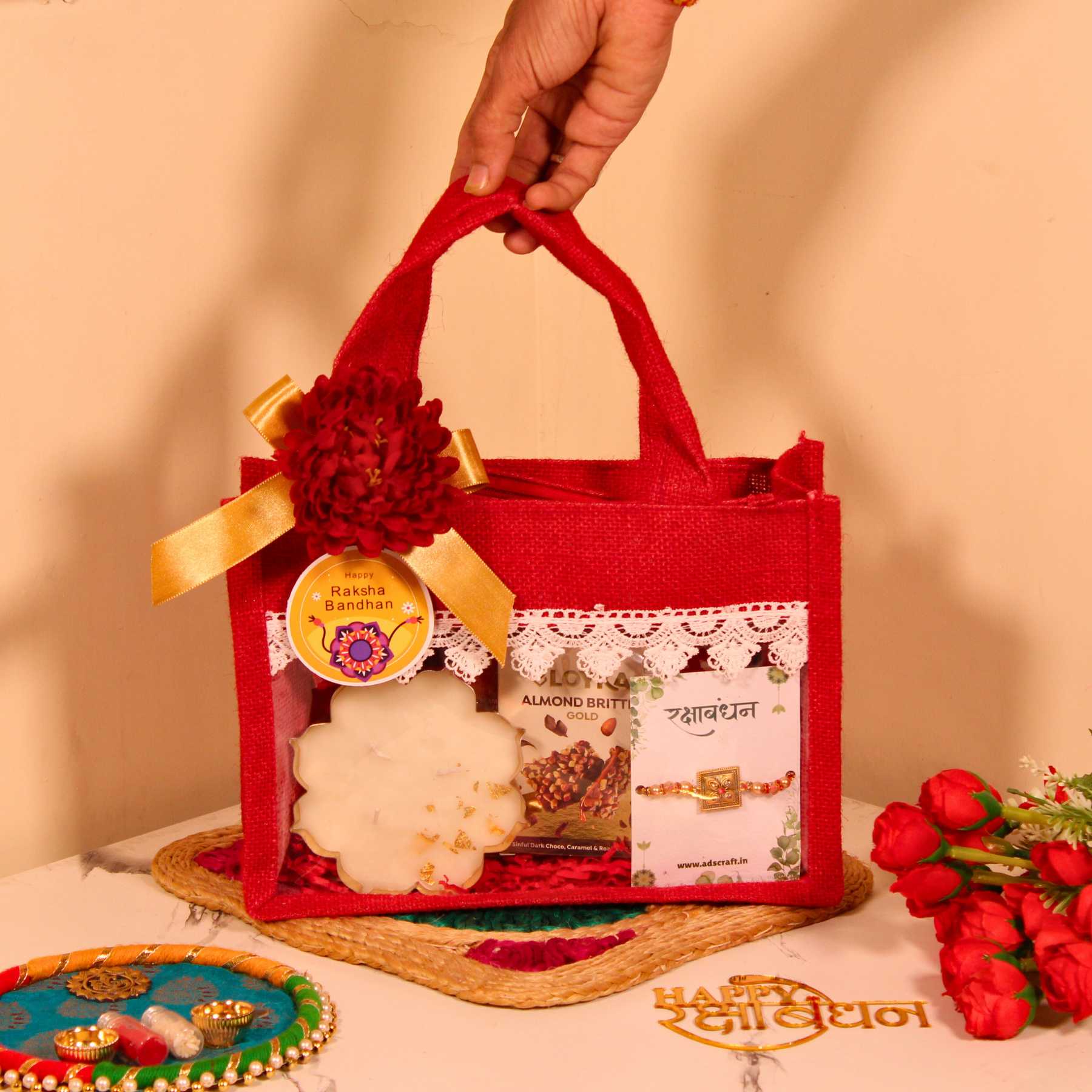 Rakhi Gift Hamper for Brother – Red Jute Bag with Party Mix, Scented Candle, Protein Bars & Rakhi