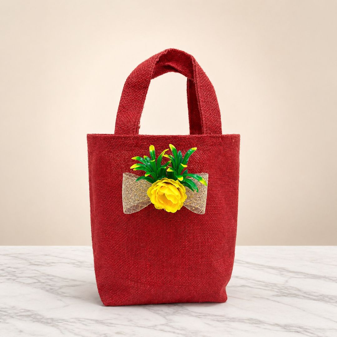 Red jute bag with a decorative yellow flower and green leaves on a marble surface.