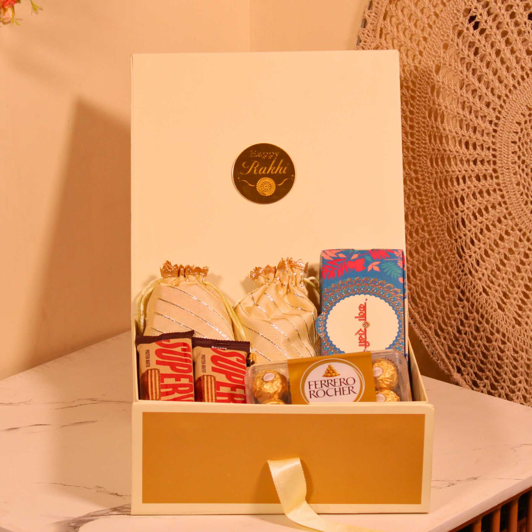 Rakhi gift hamper in cream box with dry fruits, Ferrero Rocher chocolates, and Rakhi for brother.