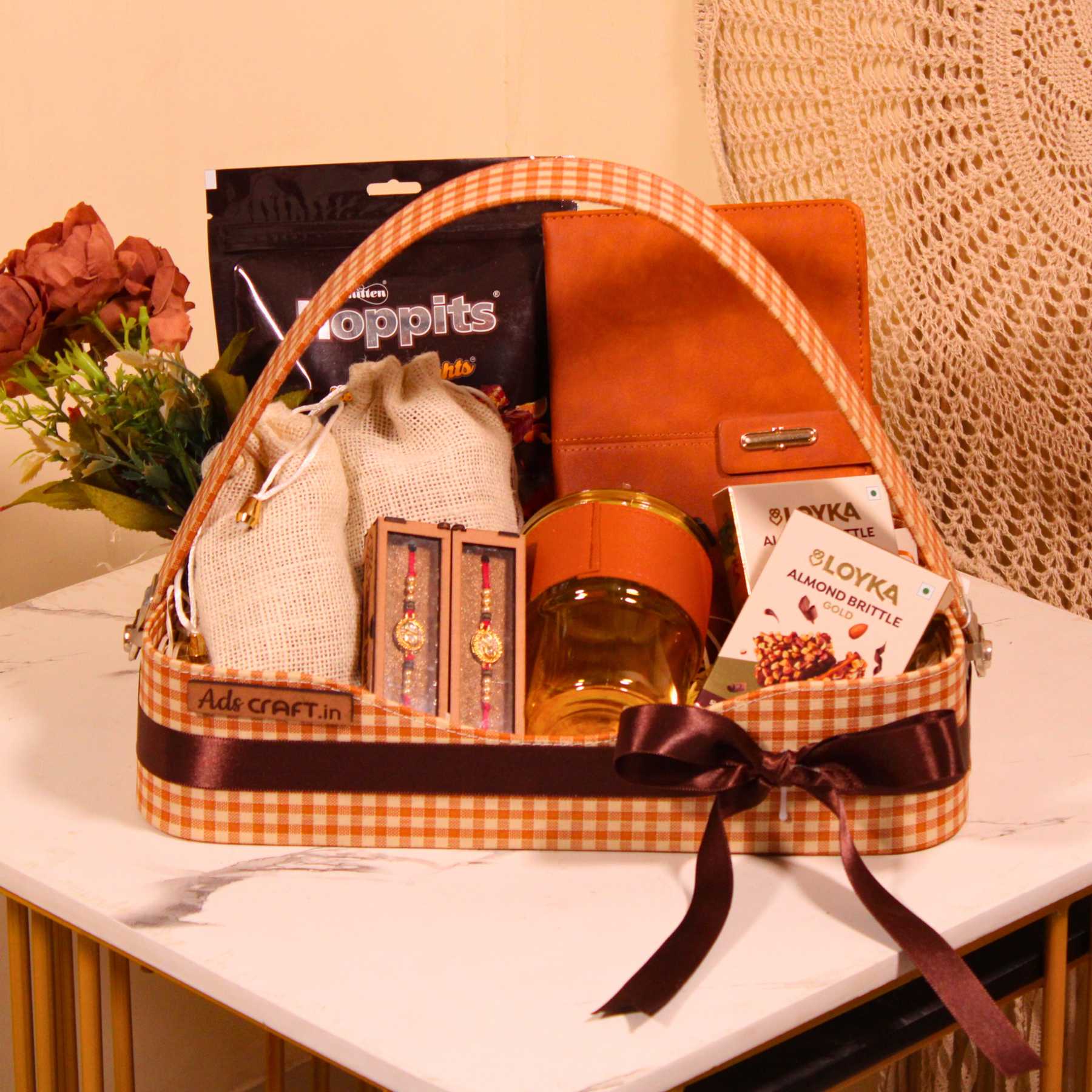 Rakhi gift hamper for brother in a brown check basket with dry fruits, Hoppits chocolate, and diary.